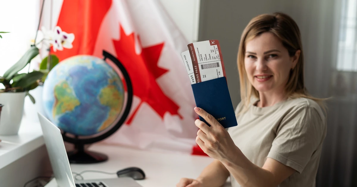 Traveller holding a passport and boarding passes beside a Canadian flag for a Canada eTA versus visitor visa guide