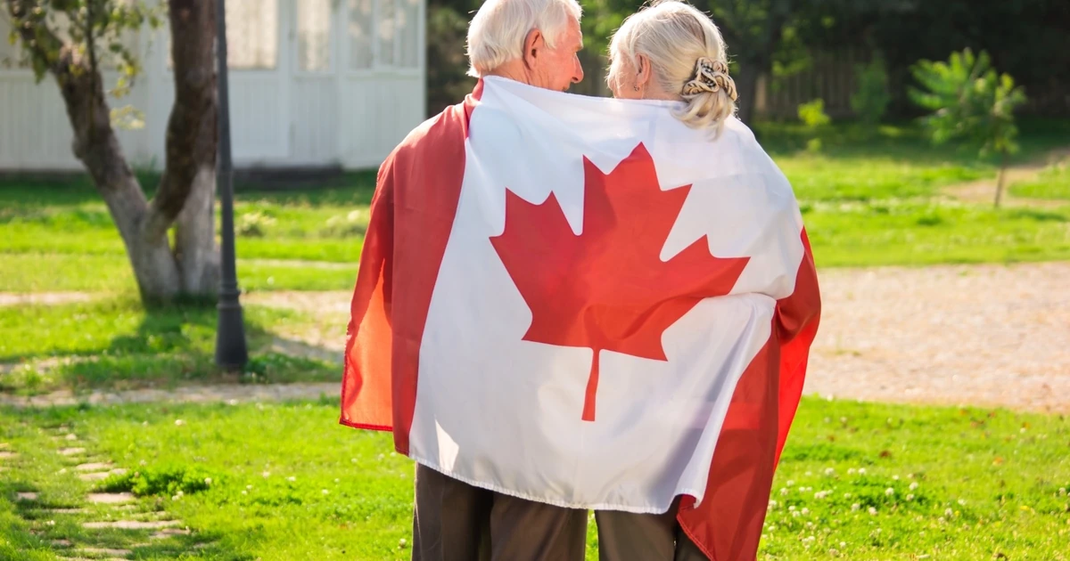 Senior parents holding a Canadian flag representing the Canada Super Visa for parents and grandparents
